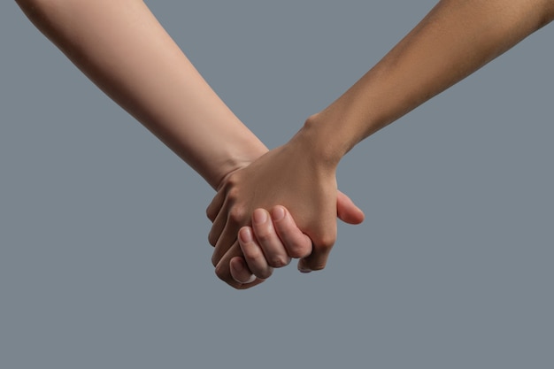 Brotherhood of mankind. Close-up of light skinned and dark skinned people holding hands