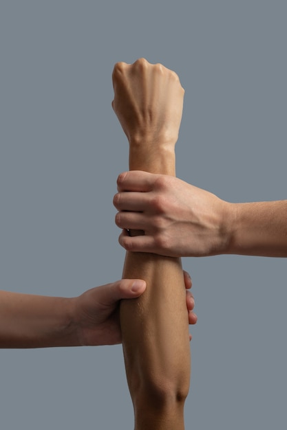 Brotherhood of mankind. Close-up of two light-skinned hands holding wrist and forearm of dark-skinned hand