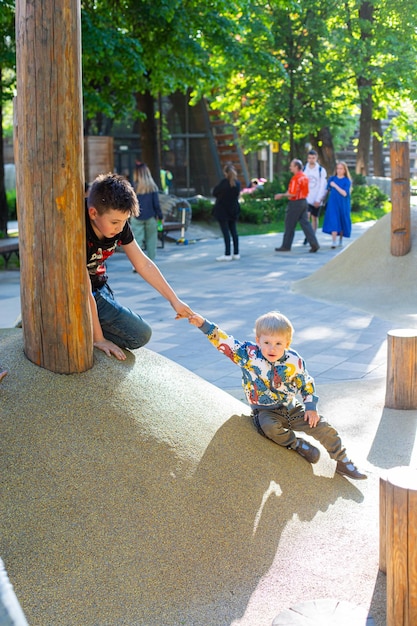 Братья играют на детской площадке летом в парке
