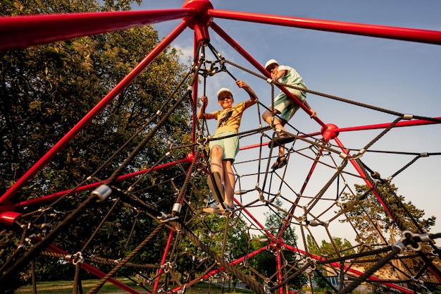 Brothers play in rope polyhedron climb at playground outdoor