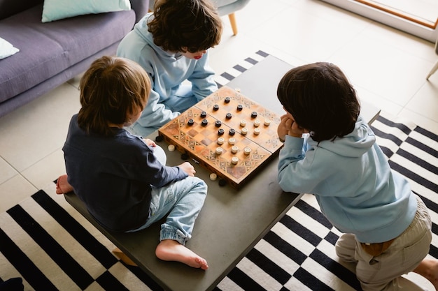 Brothers playing the checkers at home siblings playing the board strategy game spending time together