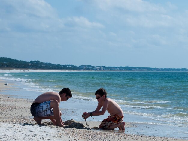 Brothers playing in sand on the Mexico Beach, Florida.