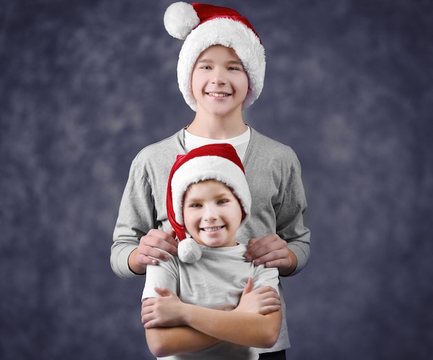 Brothers in Santa hats on grey background