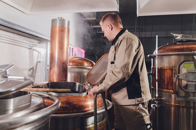 Brouwer in brouwerij die de mout in de tank giet.