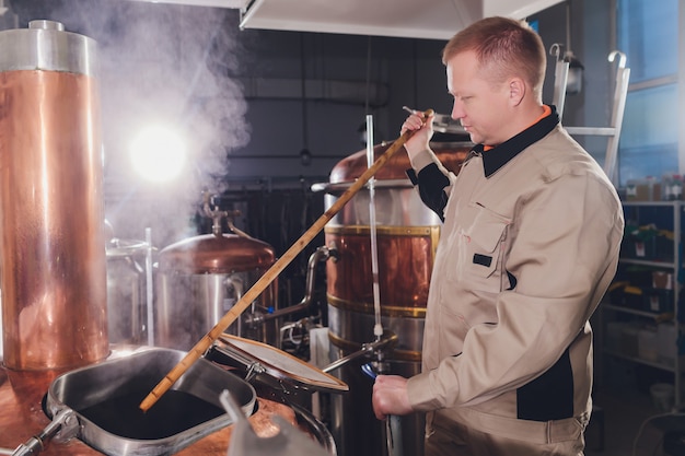 Brouwer in brouwerij die de mout in de tank giet.