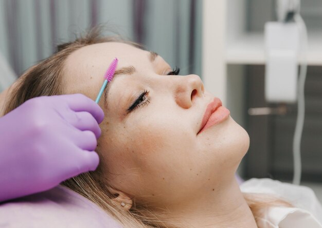 The browist combs the eyebrows with a brush eyebrow care in the salon