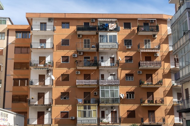 A brown apartment building with balconies and a white building in the background