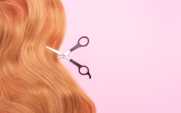 Brown artificial hair on pink and scissors