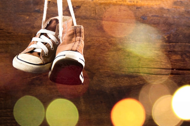Brown baby sneakers hang on wood background