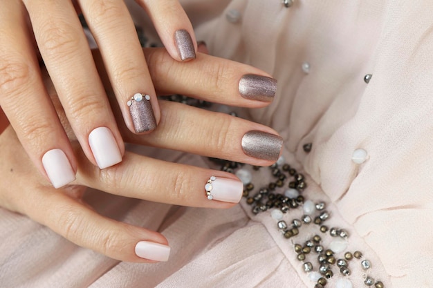 Foto manicure marrone beige con strass su unghie corte.