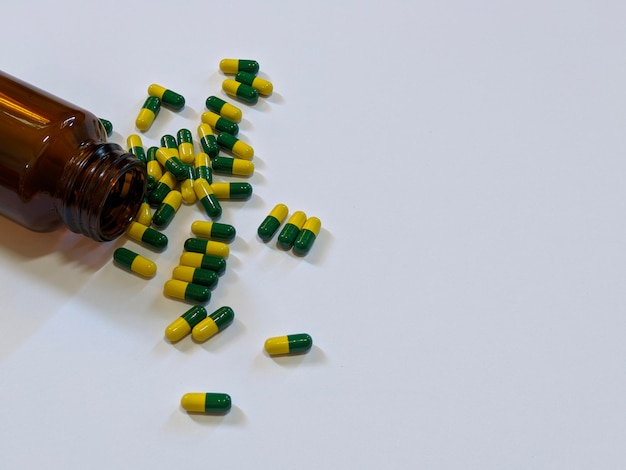 Brown bottle and green yellow capsule on isolated background