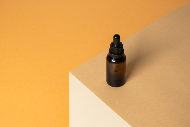 Photo brown bottle with cosmetic liquid on orange surface