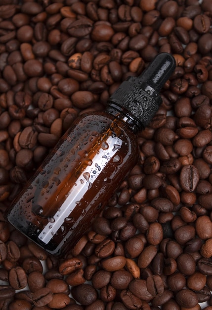 Brown bottle with dropper with a beauty serum on a black background on coffee beans Glass packaging for cosmetic product caffeine extract Skin care hydration and nutrition with collagen