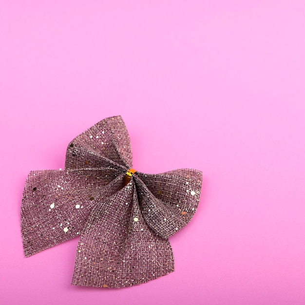 Photo brown bow with gold glitter on pastel pink background holiday decor