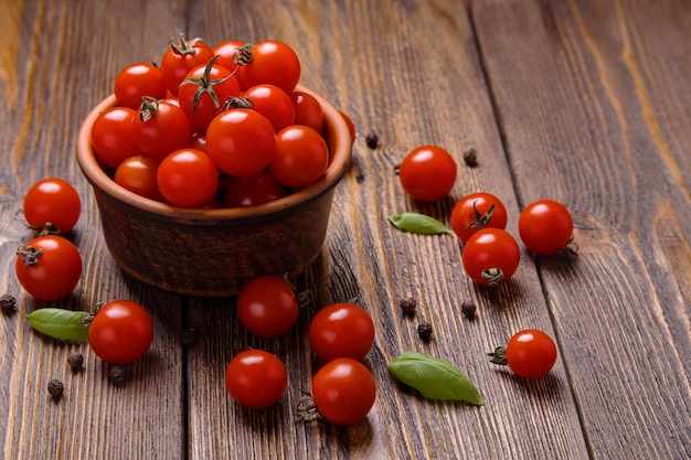 Brown bowl with cherry tomatoes on dark table top view selective focus