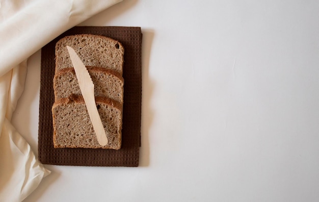 Brown bread slices with a knife on a brown table towel flat lay