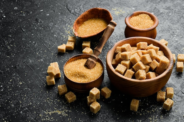 Brown cane sugar in a bowl Set of sugar On a black stone background Rustic style