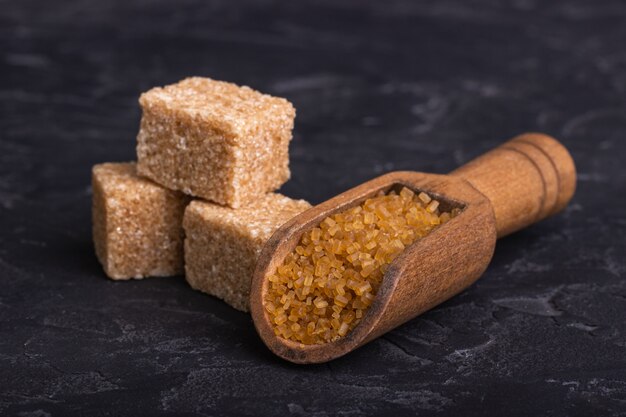 Brown cane sugar cubes in a clay bowl with a wooden spoon