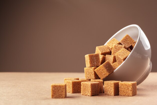 Photo brown cane sugar cubes on a light brown background