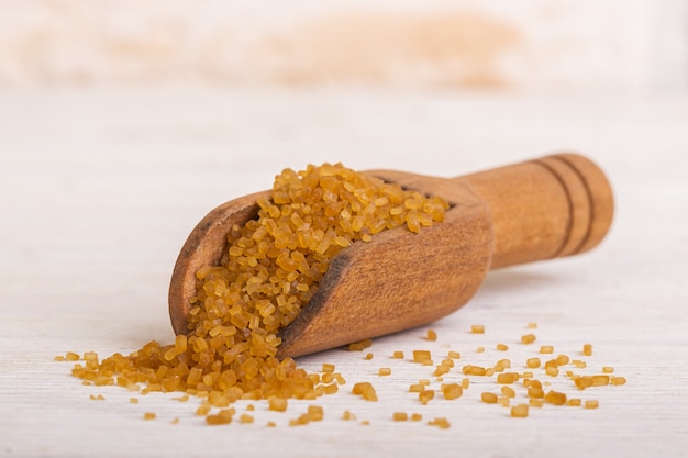 Brown cane sugar sand in a wooden spoon