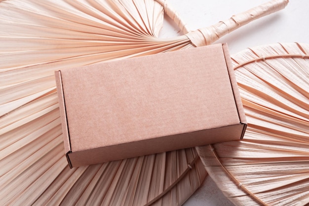 Brown cardboard box on wooden desk with dried palm fan