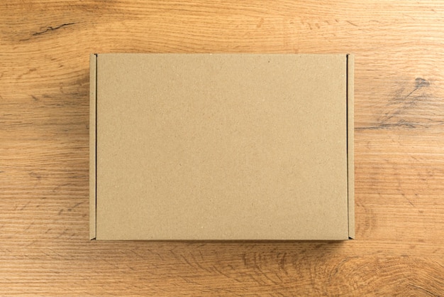 Photo brown cardboard box on wooden table background. mockup photo, concept of delivery and shipping your products and goods etc.