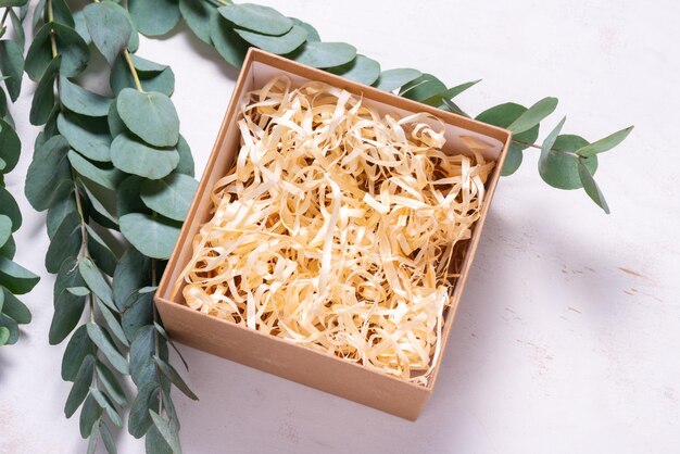 유칼립투스 녹색 가지로 장식된 충전제가 있는 갈색 판지 상자