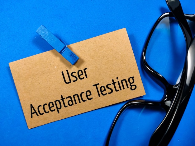 Коричневые картонные деревянные зажимы и очки с текстом User Acceptance Testing на синем фоне