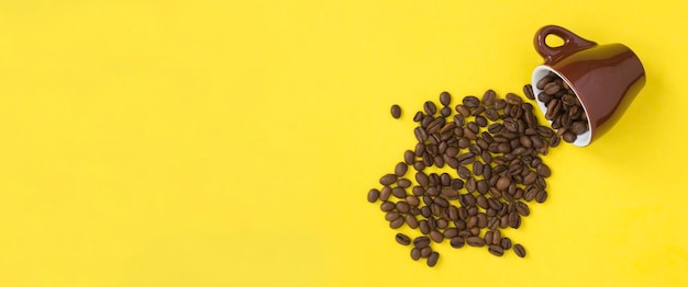 Brown ceramic cup with coffee beans on the yellow background Copy space Top view