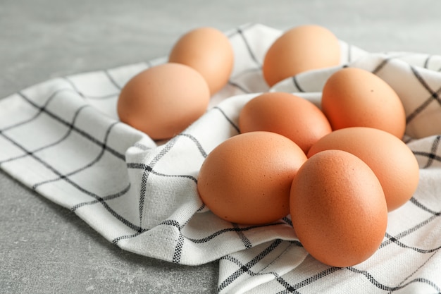 Brown chicken eggs in kitchen towel on grey