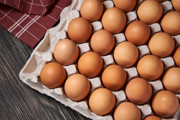 Brown chicken eggs lie in a cardboard egg tray