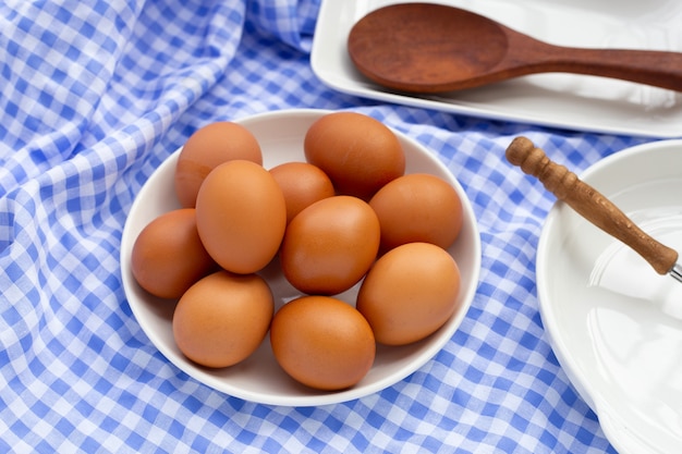 Brown chicken eggs in white plate on blue and white fabric