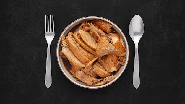 brown Chinese stewed calf of duck leg in ceramic bowl with fork and spoon on dark tone texture background top view flat lay full HD ratio Thai food Ped Pa Lo Ped Palo Ped Palow