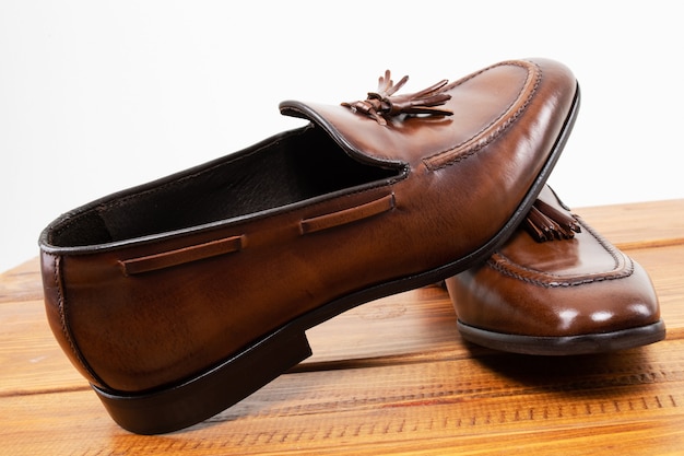 Brown classic loafers with tassels stand on a wooden stand 