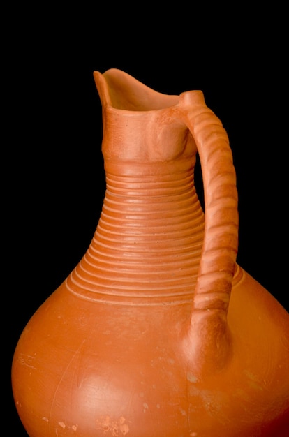 A brown clay jug isolated on a black background