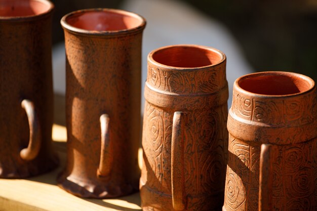 Brown clay mugs are on the shelf. handmade