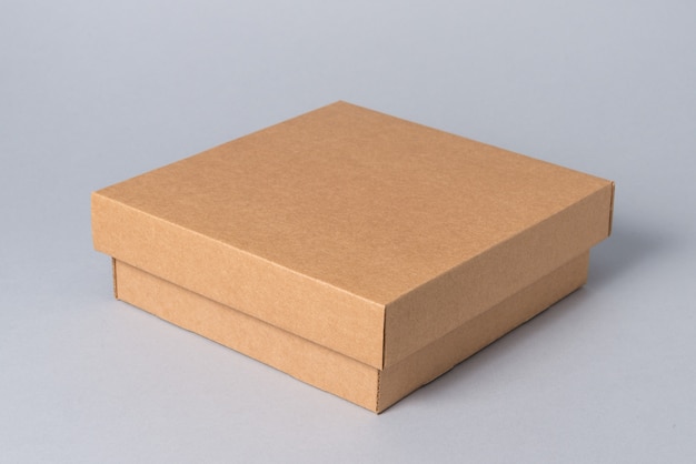 Brown closed carton gift box with cover on grey background