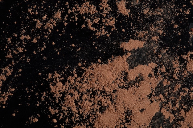 Brown cocoa powder scattered on a black background