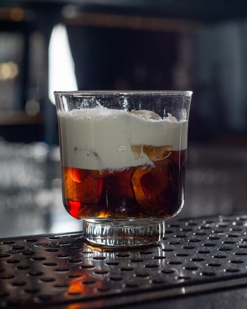 Brown cold brew coffee cocktail with cream and ice