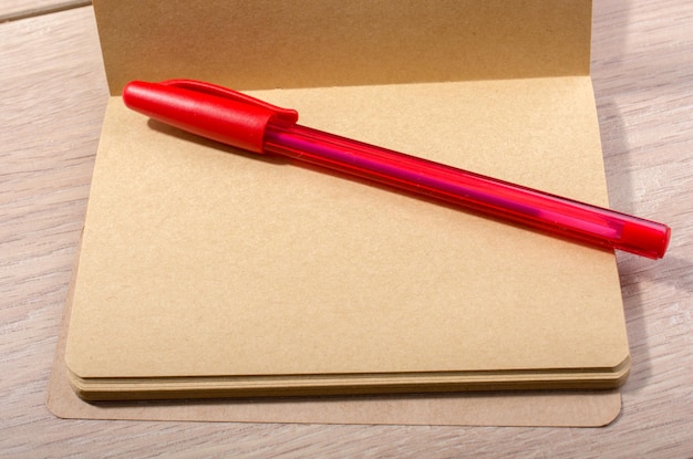 Brown color open notebook and a pen on wooden texture