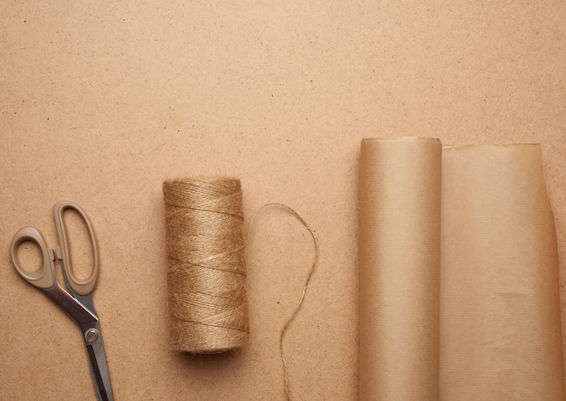 Brown craft paper roll, skein of thread and scissors