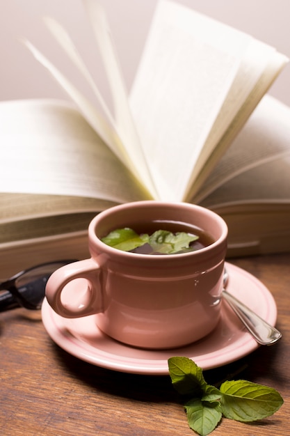 Коричневая чашка травяного чая с книгой на столе