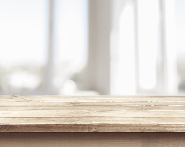 Brown desk in a white empty room lit by the sun