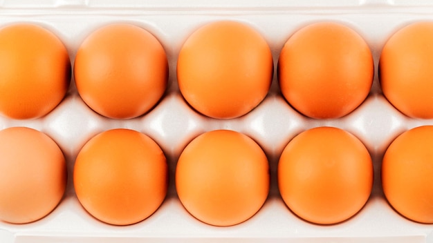 Brown eggs in plastic package on white background.