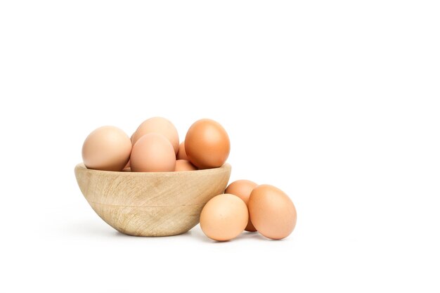 Brown eggs in a wooden bowl and on a white background with copy space