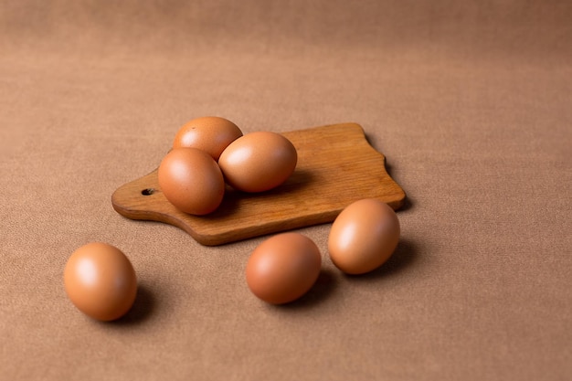 Brown eggs on a wooden cutting board on a brown background