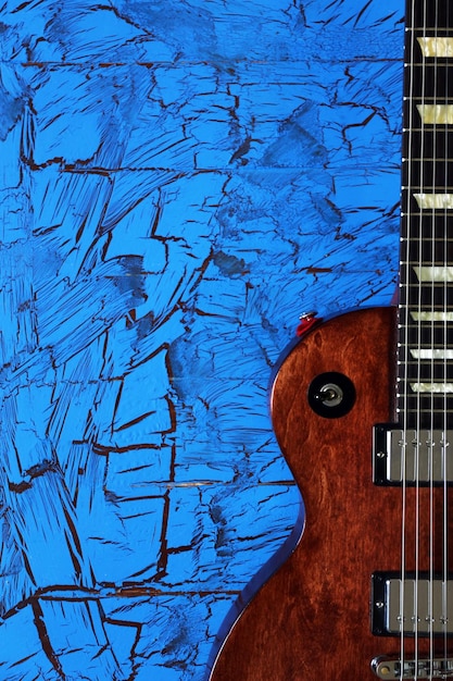 Brown electric guitar on blue wooden background