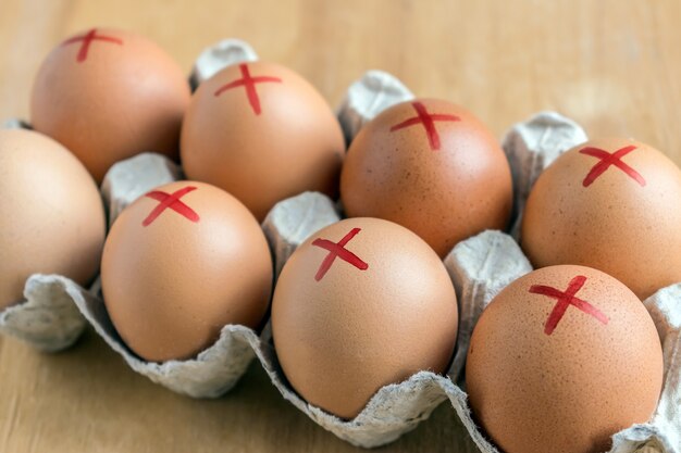 Brown farm eggs with red cross in white carton. Eggs recall