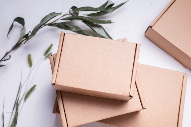 Photo brown flat cardboard carton box decorated with dried leaves, top view