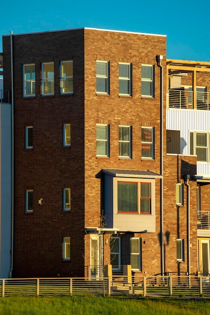 Brown four story brick building with a grassy yard and sky in the background